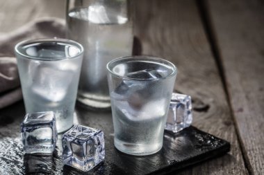 Vodka in shot glasses on rustic wood background clipart
