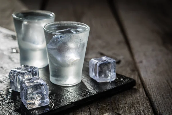 Vodka en vasos de chupito sobre fondo rústico de madera —  Fotos de Stock