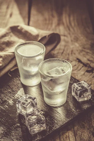 Wodka in Schnapsgläsern auf rustikalem Holzhintergrund — Stockfoto