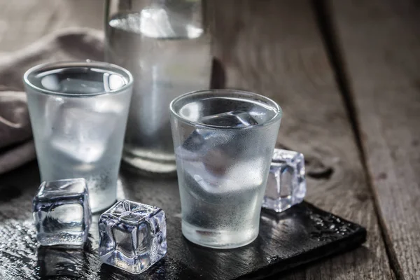 Vodka en vasos de chupito sobre fondo rústico de madera — Foto de Stock