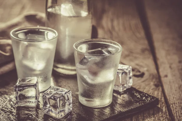 Vodka in bicchierini su sfondo in legno rustico — Foto Stock