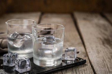 Vodka in shot glasses on rustic wood background clipart
