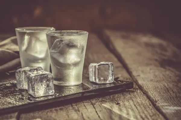 Kırsal ahşap arka planda shot bardaklarında votka