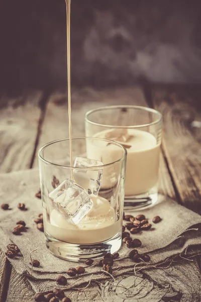 Verter el licor de café en vasos con hielo y frijoles — Foto de Stock