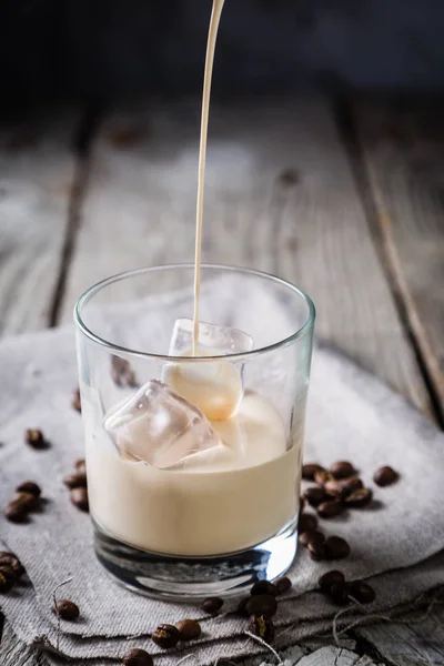 Verter el licor de café en vasos con hielo y frijoles — Foto de Stock