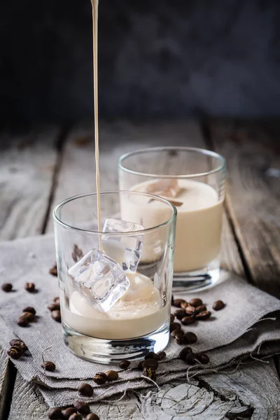 Verter el licor de café en vasos con hielo y frijoles — Foto de Stock