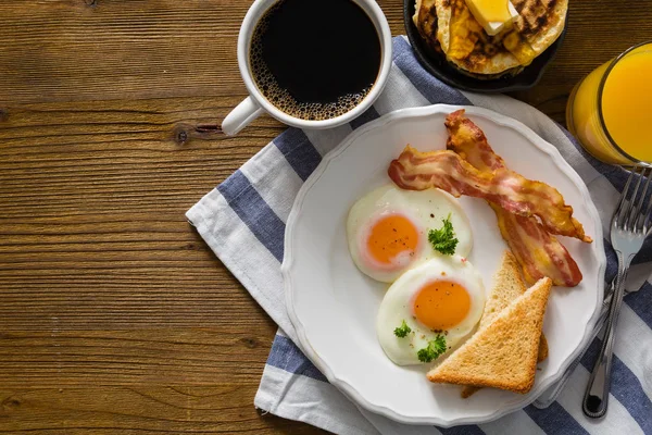 Amerikanisches Frühstück mit sonnigen Eiern, Speck, Toast, Pfannkuchen, Kaffee und Saft — Stockfoto