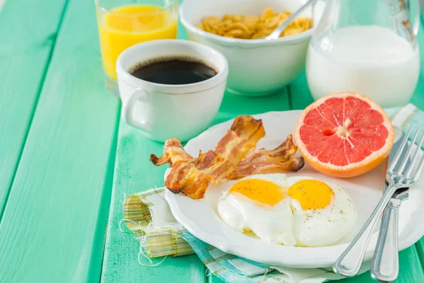 Desayuno de verano - huevos, tocino, tostadas, mermelada, café, jugo — Foto de Stock