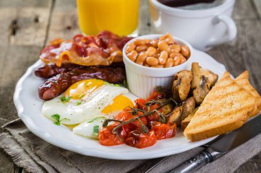 Tam İngiliz kahvaltısı - yumurta, pastırma, fasulye, kızarmış ekmek, kahve ve meyve suyu