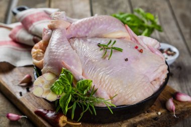 Otlar ve baharatlar rustik ahşap arka plan üzerinde ham bütün tavuk