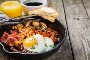 Tam İngiliz kahvaltısı - yumurta, pastırma, fasulye, kızarmış ekmek, kahve ve meyve suyu