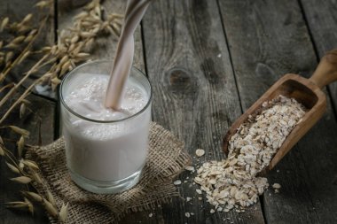 Rustik ahşap arka plan üzerinde yulaf süt dökme