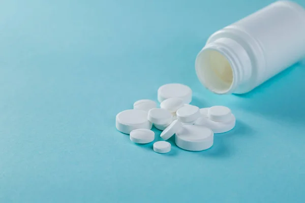 Concepto médico - diferentes formas de píldoras blancas sobre fondo azul — Foto de Stock