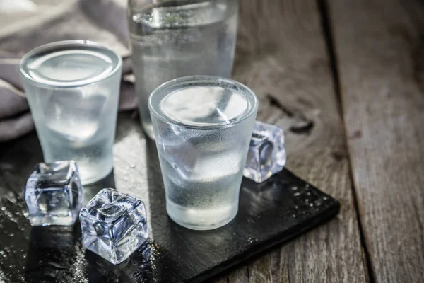 Vodka em copos de tiro no fundo de madeira rústica — Fotografia de Stock