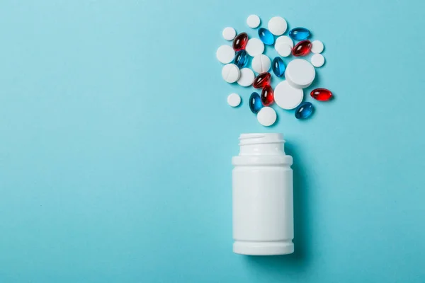Concepto médico: diferentes formas de píldoras blancas, rojas y azules sobre fondo azul — Foto de Stock