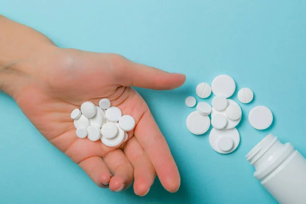 Concepto médico - diferentes formas de píldoras blancas sobre fondo azul — Foto de Stock