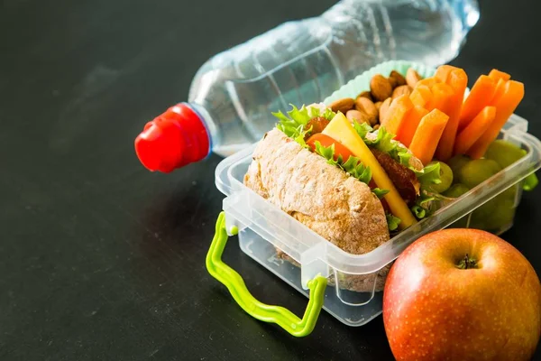 School lunch box with books and pencils in front of black board