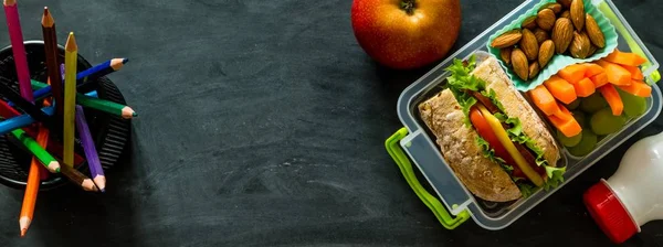 Almuerzo escolar con libros y lápices delante de pizarra negra — Foto de Stock