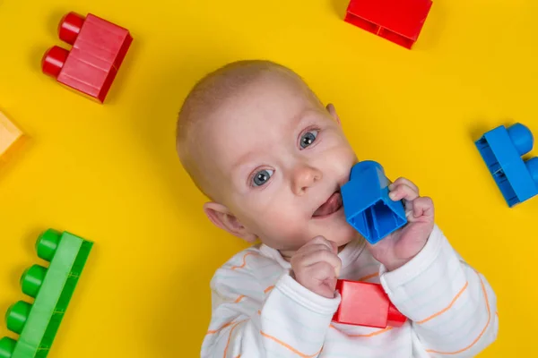 Bambino che gioca con blocchi colorati su sfondo giallo — Foto Stock