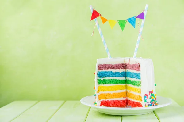 Tło urodziny - tęczy paski ciasta z biały lukier — Zdjęcie stockowe