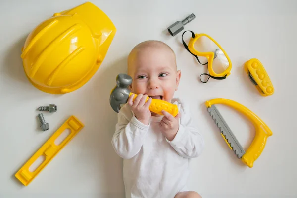 Baby spielt mit Bauwerkzeugen auf weißem Hintergrund — Stockfoto