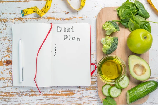 Diet plan concept - selection of green food and note pad