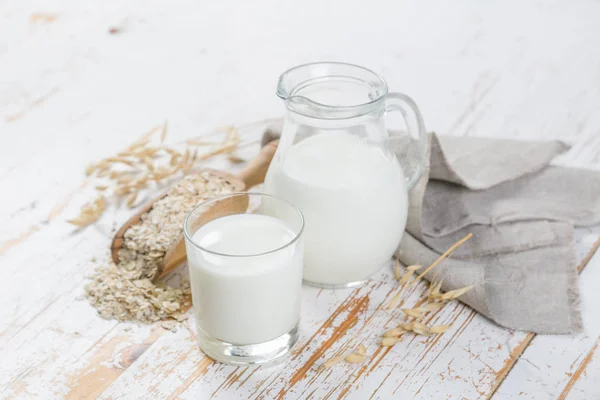 Havremjölk i glas och burk på trä bakgrund — Stockfoto