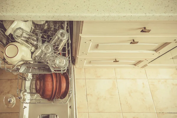 Посудомоечная машина с чистой посудой на кухонном фоне — стоковое фото
