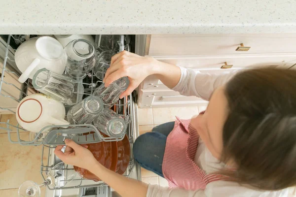 Kvinna tar rätter från diskmaskin. Hushållsarbete koncept — Stockfoto