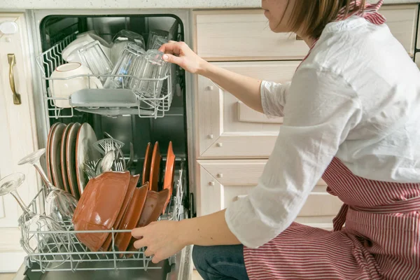 A fêmea tira os pratos da máquina de lavar louça. Conceito de trabalho doméstico — Fotografia de Stock