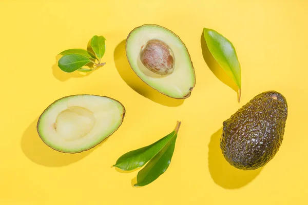 Slices of avocado on bright background. Whole and half with leaves. Design element for product label — Stock Photo, Image