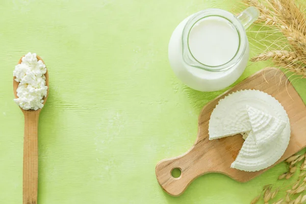 Shavuot concept - dairy products and wheat on green wood background — Stock Photo, Image