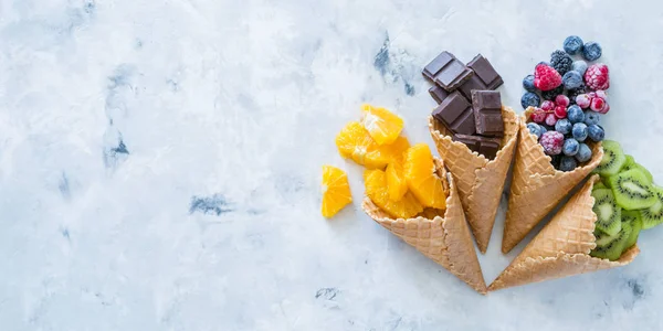 Concepto de dieta saludable - frutas y bayas congeladas en conos de helado sobre fondo rústico —  Fotos de Stock