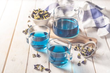 Cam fincanlarda mavi çay ve cam çaydanlık, beyaz ahşap zemin