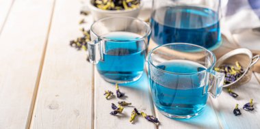 Cam fincanlarda mavi çay ve cam çaydanlık, beyaz ahşap zemin