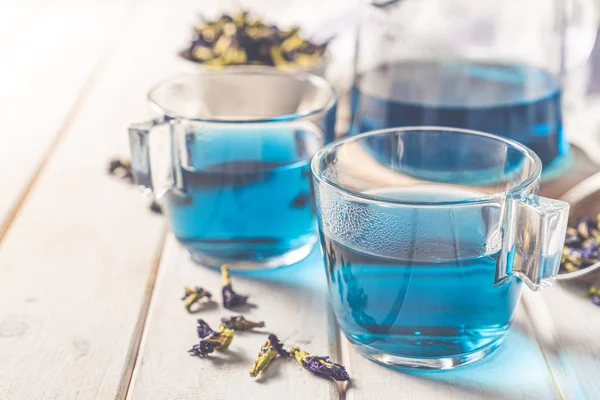 Blue tea in glass cups and glass teapod, white wood background — 스톡 사진