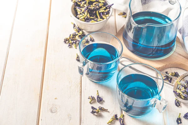 Thé bleu dans des tasses en verre et une théière en verre, fond en bois blanc — Photo