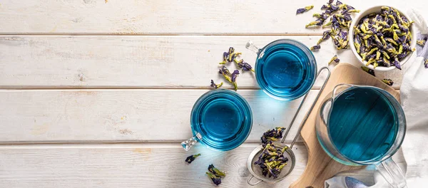 Синій чай в скляних чашках і скляній чашці, білий дерев'яний фон — стокове фото