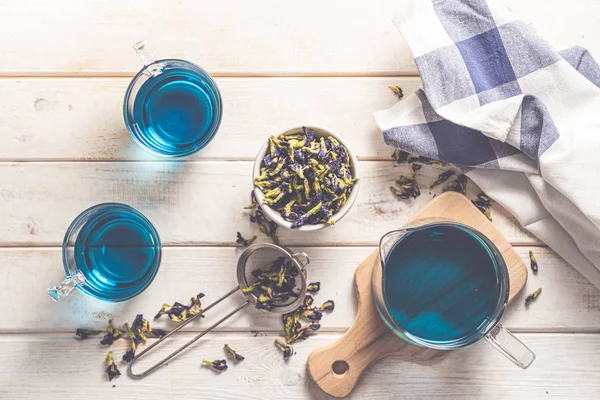 Blauer Tee in Glas Tassen und Glas Teebecher, weißer Holzhintergrund — Stockfoto