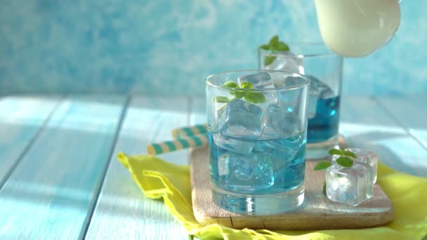 Verter leche en limonada azul sobre fondo de madera — Vídeo de stock