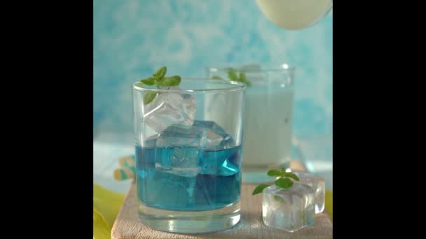 Milch in blauer Limonade auf Holz-Hintergrund gießen — Stockvideo