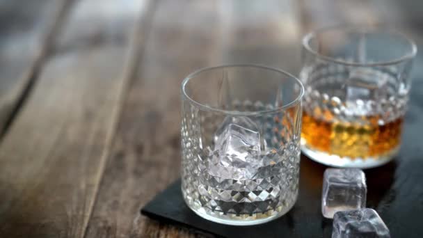 Pouring whiskey in glasses on wood background — Stock Video