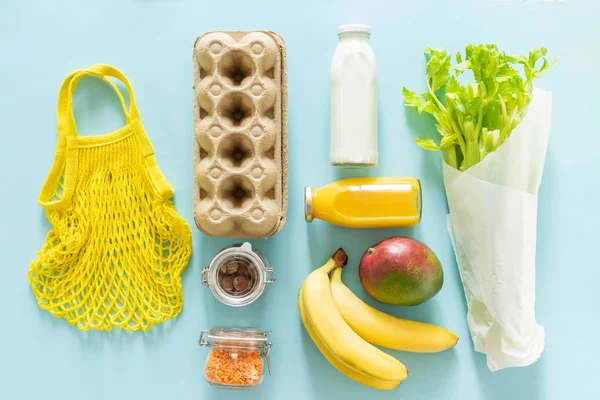 Concepto de compra de residuos cero: comestibles y bolsas reutilizables sobre fondo azul — Foto de Stock