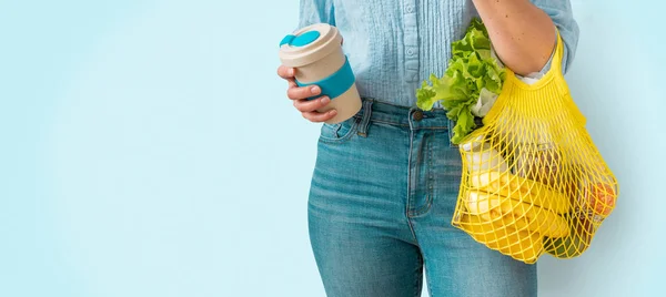 Zero odpadów zakupy - kobieta gospodarstwa żółty wielokrotnego użytku torba na zakupy i kubek kawy na jasnym tle — Zdjęcie stockowe