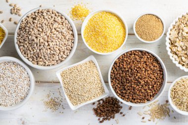 Beyaz kaselerde tam tahıl seçimi - pirinç, yulaf, karabuğday, bulgur, lapa, arpa, kinoa, amaranth,