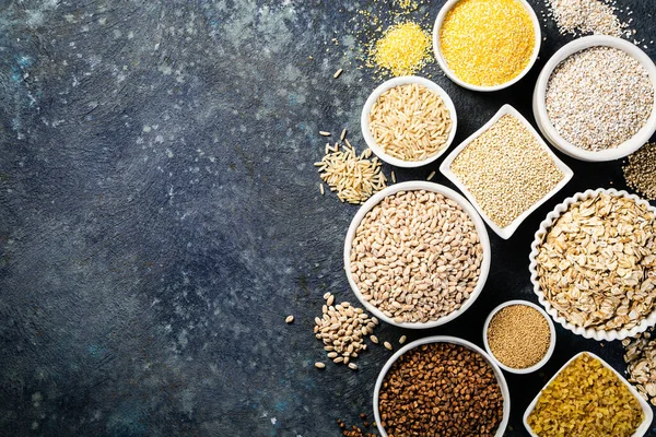 Auswahl an Vollkornprodukten in weißen Schalen - Reis, Hafer, Buchweizen, Bulgur, Haferbrei, Gerste, Quinoa, Amaranth — Stockfoto