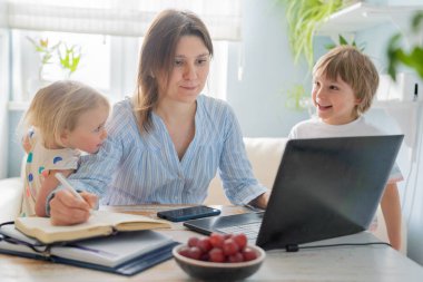 Evden çalışan bir kadın, çocuklar koşuyor ve çığlık atıyorlar.