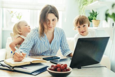 Evden çalışan bir kadın, çocuklar koşuyor ve çığlık atıyorlar.