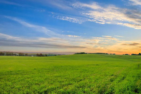 Pôr do sol em terras cultivadas no campo em um verão . — Fotografia de Stock