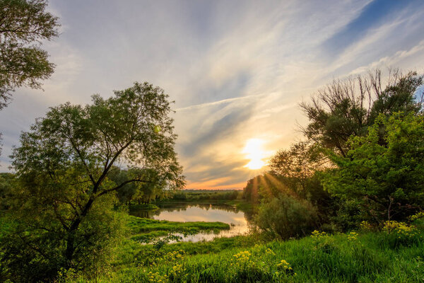 Sunset above the river at summer with cloudy sky background.